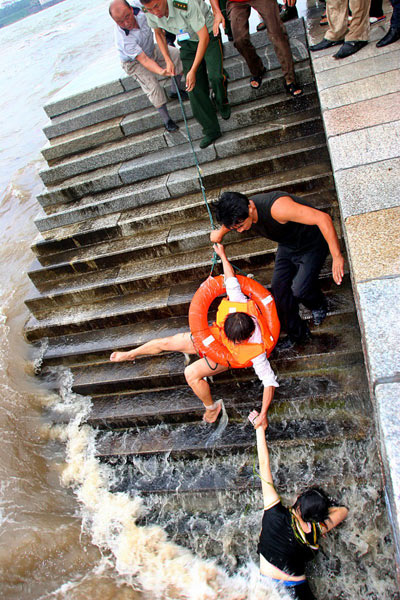 Rescue workers try to pull Wei Qing, a migrant worker, up using a life preserver as he tries to maintain his hold on a girl who was nearly swept into Shazikou Bay in Qingdao, East China's Shandong Province, during Typhoon Matsa on August 5, 2005.