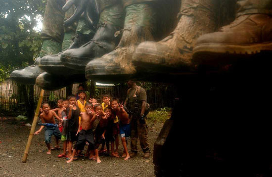 Children smile and flash the "peace sign" to a passing truck carrying United States soldiers participating in the search and rescue operation for victims of a landslide in Baranggay Guinsaugon, St. Bernard, Southern Leyte, the Philippines, on February 23, 2006.