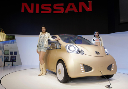 Models stand next to a Nissan Nuvu car
