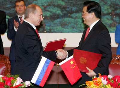 Chinese President Hu Jintao (R) exchanges a contract with Russian President Vladimir Putin during a signing ceremony at the Great Hall of the People in Beijing March 21, 2006. [Reuters]
