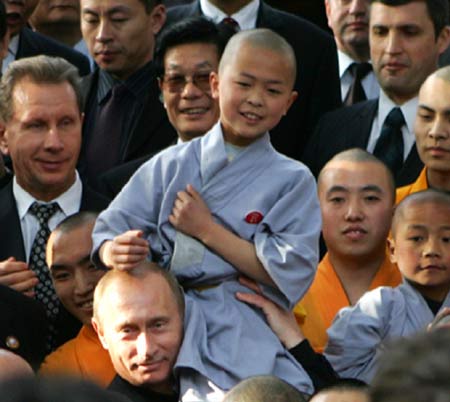 Russian President Vladimir Putin perches a monk on his head during a visit to the Shaolin Temple in Central China's Henan Province March 22, 2006. Shaolin Temple is widely believed as the origin of martial arts. [Reuters] 