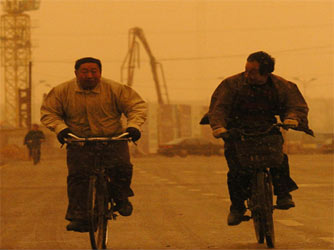 Residents ride bicycles through a sand storm on a street in Shenyang, Northeast China's Liaoning Province Monday March 27, 2006. [Xinhua] 