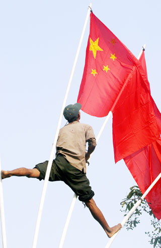 A Cambodian worker puts up Chinese national flags on the street in Phnom Penh April 7, 2006. China's Prime Minister Wen Jiabao will arrive in Cambodia on Friday for a two-day official visit. 