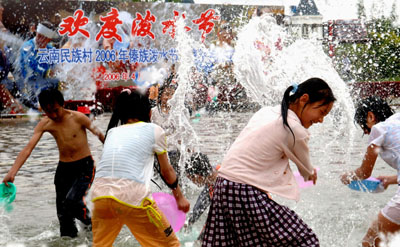 Chinese tourists and Dai people celebrate the traditional water-splashing festival in an ethnic garden in Southwest China's Yunnan Province Aprial 11, 2006. The annual Water-Splashing Festival is most important holiday of the Dai people. Held during the sixth month of the Dai calendar, the festival is usually falling in the middle of April and is also known as the Festival for Bathing the Buddha. [Xinhua]