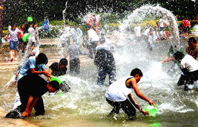 Chinese tourists and Dai people celebrate the traditional water-splashing festival in an ethnic garden in Southwest China's Yunnan Province Aprial 11, 2006. The annual Water-Splashing Festival is most important holiday of the Dai people. Held during the sixth month of the Dai calendar, the festival is usually falling in the middle of April and is also known as the Festival for Bathing the Buddha. [Xinhua]