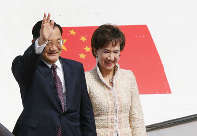 Kuomintang's honorary chairman Lien Chan (L), and his wife are presented with floral bouquets as they arrive at Hong Kong International Airport April 13, 2006. Lien Chan is leading a KMT delegation from Taiwan to Beijing via Hong Kong.