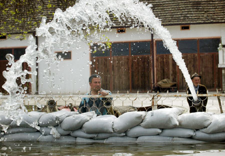 Villagers watch a pump remove water from their yard, near the Danube River, in the village of Ritopek near Belgrade April 17, 2006. The Danube peaked at record highs in Serbia on Monday without overwhelming flood defences, but authorities warned there was still danger waterlogged dykes could collapse and wreak havoc across southeastern Europe.