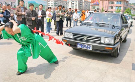 Chinese woman Zhang Ting (C) pulls three cars using her hair during a stunt performance at a park in Nanjing, capital of east China's Jiangsu province April 24, 2006. Zhang successfully pulled the three car for 20 meters.