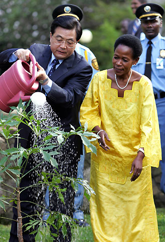 President Hu Jintao (L) is assisted by the UN Habitat executive director Anna Tibaijuka as he planted a tree at the UN compound in Nairobi, April 28, 2006. 
