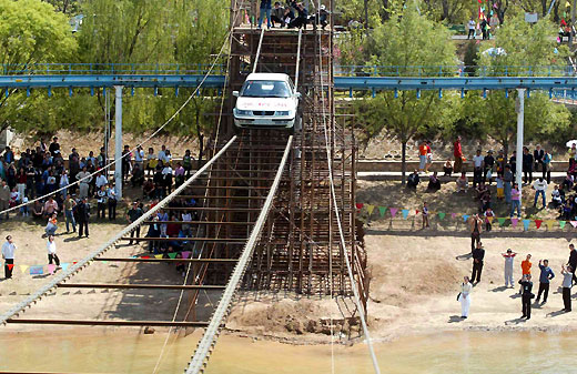 A Guinness World Records holder Yang Xiangdong drives a car through 60-meter steel tightrope at the Yanxi Lake in Beijing May 2, 2006. China is celebrating a week-long Labour Day holiday, which starts yesterday, a time when millions of Chinese people travel to major cities to enjoy cultural attractions or return home to visit relatives and friends. [newsphoto]