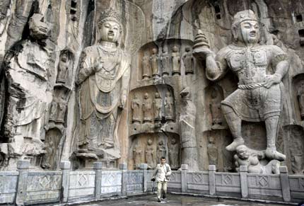 A foreign visitor walks in front of huge sculptures at Longmen Grottoes in the city of Luoyang in China's central province of Henan May 12, 2006. "Longmen Grottoes" is one of China's UNESCO World Heritage sites in Henan Province. Longmen has more than 2,300 grottoes with 110,000 Buddhist images, over 80 dagobas and 2,800 inscribed tablets on cliffs with a length of one kilometer along the Yishui River, where Buddhism was first introduced to China during the Eastern Han Dynasty (25 - 220), according to Xinhua News. [Reuters]