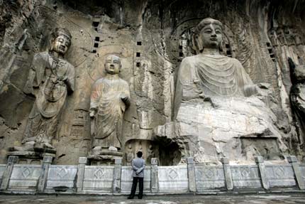 A visitor is dwarfed by huge sculptures at Longmen Grottoes in the city of Luoyang in China's central province of Henan May 12, 2006. "Longmen Grottoes" is one of China's UNESCO World Heritage sites in Henan Province. Longmen has more than 2,300 grottoes with 110,000 Buddhist images, over 80 dagobas and 2,800 inscribed tablets on cliffs with a length of one kilometer along the Yishui River, where Buddhism was first introduced to China during the Eastern Han Dynasty (25 - 220), according to Xinhua News. [Reuters]