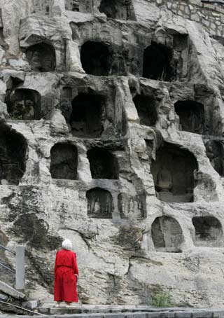 A tourist views Longmen Grottoes in the city of Luoyang in China's central province of Henan May 12, 2006. "Longmen Grottoes" is one of China's UNESCO World Heritage sites in Henan Province. Longmen has more than 2,300 grottoes with 110,000 Buddhist images, over 80 dagobas and 2,800 inscribed tablets on cliffs with a length of one kilometer along the Yishui River, where Buddhism was first introduced to China during the Eastern Han Dynasty (25 - 220), according to Xinhua News. [Reuters]