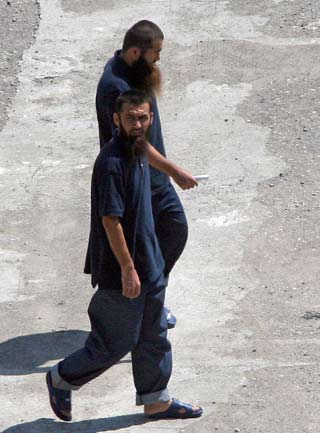 Two of five Chinese suspects, released from the US-run Guantanamo prison, walk in an Albanian refugees center in Tirana May 12, 2006. The Chinese government has demanded immediate return of five Chinese nationals who are by no means refugees but terrorist suspects, said Foreign Ministry spokesman Liu Jianchao. The five from Northwest China's Xinjiang Uygur Autonomous Region are suspected of being members of the East Turkistan Islamic Movement. They were held in Guantanamo for several years after being picked up during the US invasion of Afghanistan following the September 11, 2001, terrorist attacks. [Reuters]