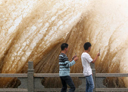 Chinese men take snapshotsas strong waves whip a bridge in Zhuhai, Guangdong province May 17, 2006. Typhoon Chanchu continues to move northward along the coastal areas of east China's Fujian Province after it landed in Guangdong. [Xinhua]
