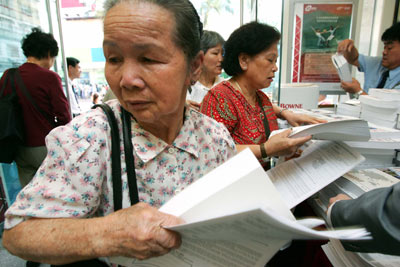 Residents collect prospectuses for the initial public offering of Bank of China in Hong Kong, May 18, 2006. 