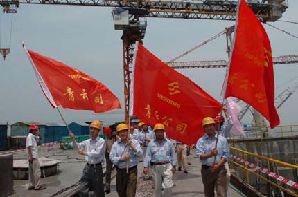 Builders of the Three Gorges Project, hold red flags in celebrating the completion of concrete placement of the mammoth Three Gorges dam, Saturday afternoon May 20, 2006. Construction crews finished the main dam structure of the world's largest hydroelectric project on Saturday, Xinhua reported. [Xinhua]