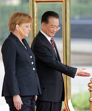 Chinese Premier Wen Jiabao (R) shows the way to German Chancellor Angela Merkel during a welcome ceremony outside the Great Hall of the People in Beijing May 22, 2006. Merkel is on an official two day visit to China 