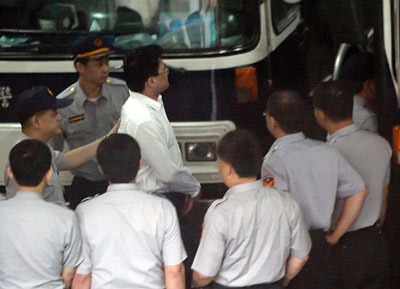 The handcuffed son-in-law of Taiwan leader Chen Shui-bian is led by police to a bus after being taken into custody on suspicion of insider trading, in Taipei May 25, 2006. Chao Chien-ming, a doctor married to Chen's daughter, was taken into custody after prosecutors and the Bureau of Investigation questioned him for about 15 hours, prosecutor Lin Ban-liang said. [Reuters]