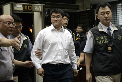 Chao Chien-ming, a doctor married to Taiwan leader Chen Shui-bian's daughter, is escorted by Bureau of Investigation agents in Taipei May 24, 2006. Chao and four members of Chen's family were questioned for an insider trading scandal. [Reuters]