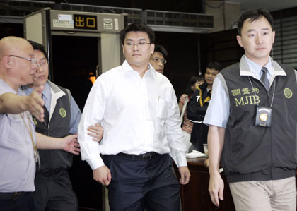 Chao Chien-ming, a doctor married to Taiwan President Chen Shui-bian's daughter, is escorted by Bureau of Investigation agents in Taipei May 24, 2006. Chao and four members of Chen's family were questioned on Wednesday by Bureau of Investigation agents probing a snowballing insider trading scandal. 