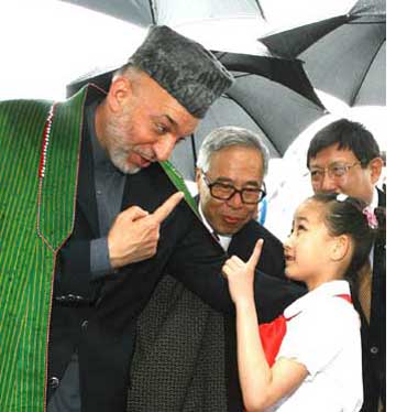 Afghan President Hamid Karzai (L) talks with a Chinese girl after arriving at the Pudong International Airport in Shanghai, east China on June 14, 2006.