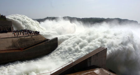 Visitors look at the water gushing from Xiaolangdi Reservoir on the Yellow River in Central China's Henan Province June 15, 2006. About 3000 cubic meters per second of water will be discharged out of the reservoir for next 15 days to wash the sands in the riverbed into the sea. [newsphoto]
