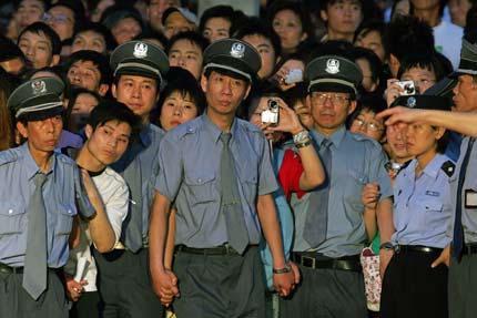 Security personnel stand guard in front of fans at the opening ceremony of the Shanghai International Film Festival at the Shanghai Concert Hall June 17, 2006. [Reuters]
