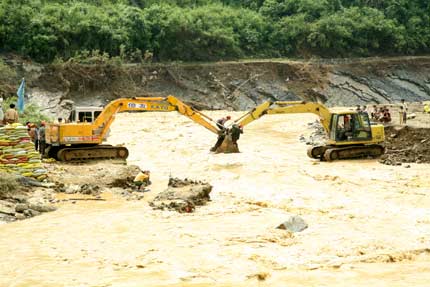 Chinese villagers and rescuers build a temporary bridge after floods destroyed the original one in Wangmo, southwest China's Guizhou province, June 17, 2006. Heavy rainstorms hit Wangmo again, where flash floods have killed at least 52 people, with another 20 still missing earlier this month, Xinhua reported. [Newsphoto]