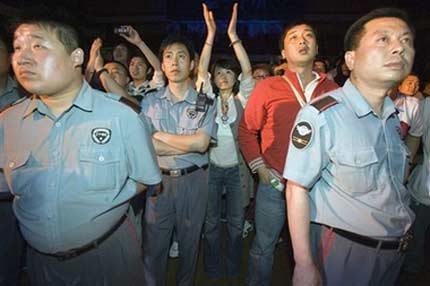 Chinese security guards stand in front of rock fans during a concert directed by Chinese rock music icon Cui Jian to mark the 20th anniversary of rock music in China held at an indoor stadium in Shenyang, north China's Liaoning province, Friday, June 16, 2006. Cui Jian introduced rock music to China with his song 'I Own Nothing' in 1986. [AP Photo]