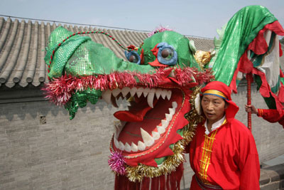 A performer carries a dragon on the Chinese Wall at Badaling during a ceremony to start the fourth Beijing Olympic arts festival June 23, 2006. [Reuters]