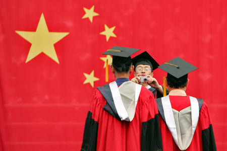 A student takes a picture of his friends in front of the Chinese flag during a graduation ceremony at Fudan University in Shanghai June 28, 2006.[