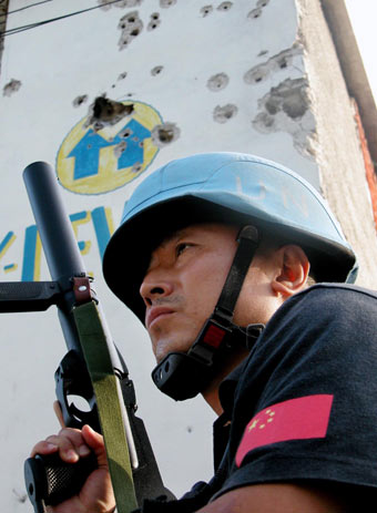 An armed UN Chinese peacekeeper stands guard near a church during a religious celebration of the local residents in Port-au-Prince, the Haitian Capital, June 27, 2006. Currently, there are 125 Chinese peacekeepers in Haiti. [Newsphoto]