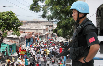An armed UN Chinese peacekeeper stands guard near a church during a religious celebration of the local residents in Port-au-Prince, the Haitian Capital, June 27, 2006. Currently, there are 125 Chinese peacekeepers in Haiti. [Newsphoto]