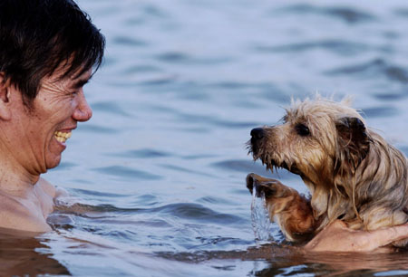 A local resident plays with his pet in the water to cool themselves off in Fuzhou, capital of east China's Fujian Province Monday, Junly 3, 2006. A heat wave is expected to hit parts of China over the next week with temperatures reaching up to 37 Degree Celsius (98 degrees Fahrenheit). [Xinhua]