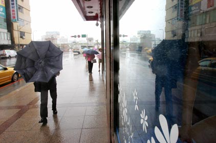 Pedestrians are buffeted by heavy rains and strong winds from tropical storm Bilis in front of a train station in Taipei July 13, 2006. [Reuters]
