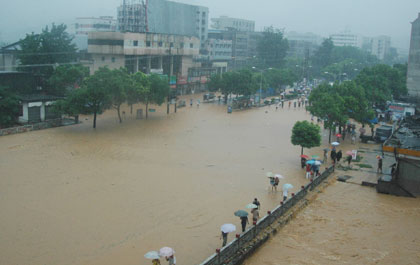 People wades through a flooded street in Chenzhou, Hunan province July 15, 2006. Typhoon Bilis brough heavy rains to several provinces, leaving 42 dead and more than 100 missing. [Xinhua]