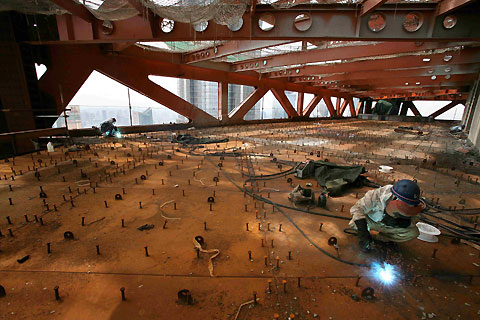 Construction workers chat on the 42nd floor of the Shanghai World Financial Center building site in Shanghai July 24, 2006. The building, which will stand at 101 storeys and 492 metres when completed in 2008, aims to be the tallest building in China. [Reuters]