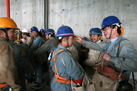 Construction workers chat on the 42nd floor of the Shanghai World Financial Center building site in Shanghai July 24, 2006. The building, which will stand at 101 storeys and 492 metres when completed in 2008, aims to be the tallest building in China. [Reuters]