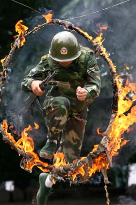 A Chinese soldier jumps through a fire ring during an anti-terror training in Suining, Southwest China's Sichuan Province, July 24, 2006. [newsphoto]