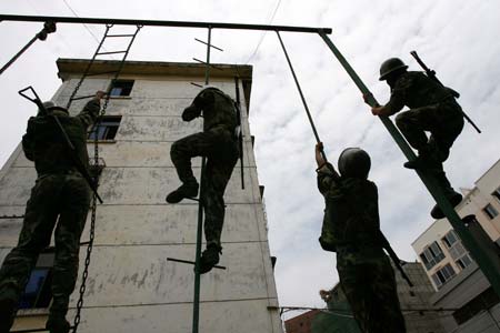 A Chinese soldier stands guard as others climb a building during an anti-terror training in Suining, Southwest China's Sichuan Province, July 24, 2006. [newsphoto]