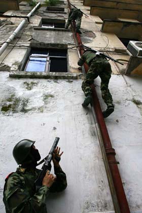 A Chinese soldier stands guard as others climb a building during an anti-terror training in Suining, Southwest China's Sichuan Province, July 24, 2006. [newsphoto]
