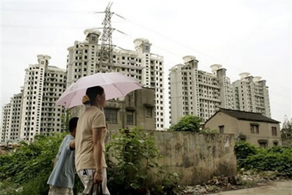 Neighbors walk past old houses to be demolished to build new apartment complex with new apartment buildings under construction as background Monday, July 24, 2006 in Shanghai, China. China on Monday released proposed rules to limit foreign investment in real estate amid quickening efforts to cool off the surging economy, an official news agency said.