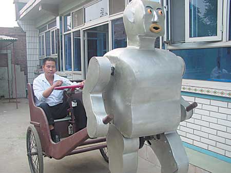 A 1.8-metre-high silver robot, strides its heavy feet along a narrow street, pulling a rickshaw behind it. 