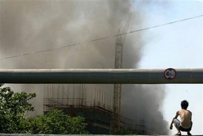 A man looks at smoke coming from a chemical plant after two silos storing hydrogen peroxide exploded in Shanghai, in east China Friday July 28, 2006. An explosion and fire ripped through a plant belonging to the Shanghai Yuanda Peroxide Co. Ltd., seriously injuring at least four people and throwing up thick smoke across the Baoshan industrial district to the city's north. (AP Photo)