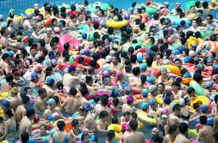 Thronging swimmers stand in Taiyanggong Swimming Pool in Nanjing, capital of east China's Jiangsu Province Sunday, July 30, 2006, as the local temperature hit 36.2 degrees centigrade. With the abundant people going there to beat the heat, swimmers can only stand in the water rather than swim freely. [IC]