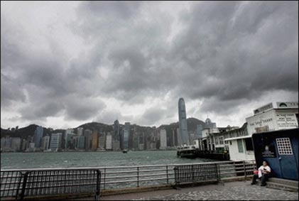 A man sits looking at the stormy sky over the Hong Kong island skyline as strong winds and rain lash the territory. Typhoon Prapiroon killed five people in Guangdong province after making landfall on Friday, pounding the area with torrential rains and gale force winds.(