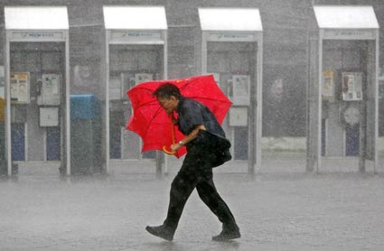 A man walks in the rain along a street in Hong Kong Aug 3, 2006. Typhoon Prapiroon, which killed six people and forced thousands to flee their homes in the northern Philippines, churned towards southern China on Thursday and tens of thousands were evacuated ahead of its arrival.[Reuters]