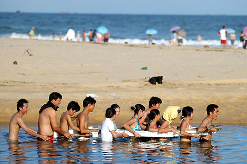 Tourists wade on the seaside as scenic spots in China's south Hainan Province reopened after the attack of the Typhoon Prapiroon. Photo is taken on August 5, 2006. [Xinhua]