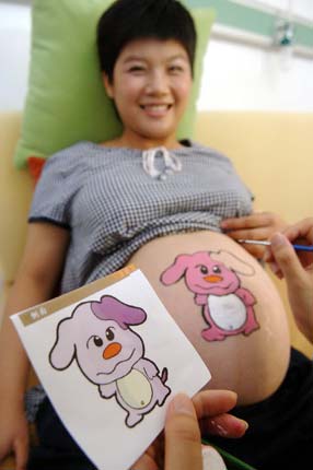 An artist paints on the belly of a pregnant woman during a contest at a hospital in Haikou, South China's Hainan Province August 7 2006. [Zhao Yingquan/Xinhua]